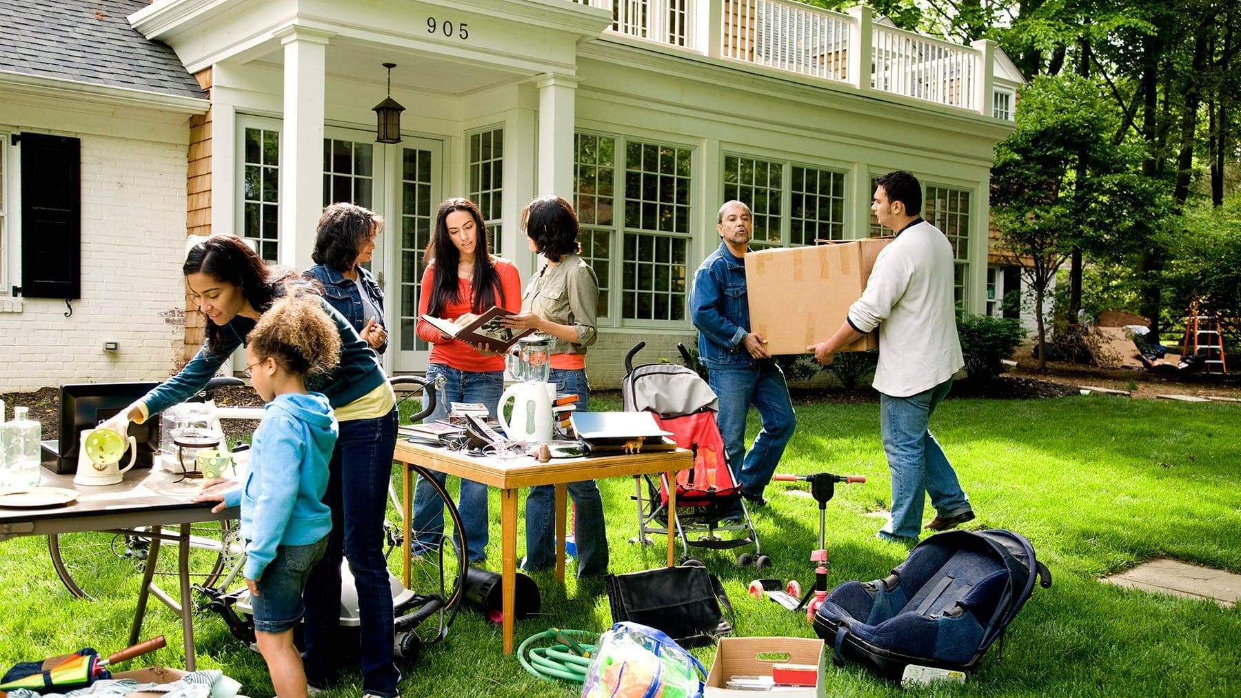 family setting up an estate sale on the front lawn