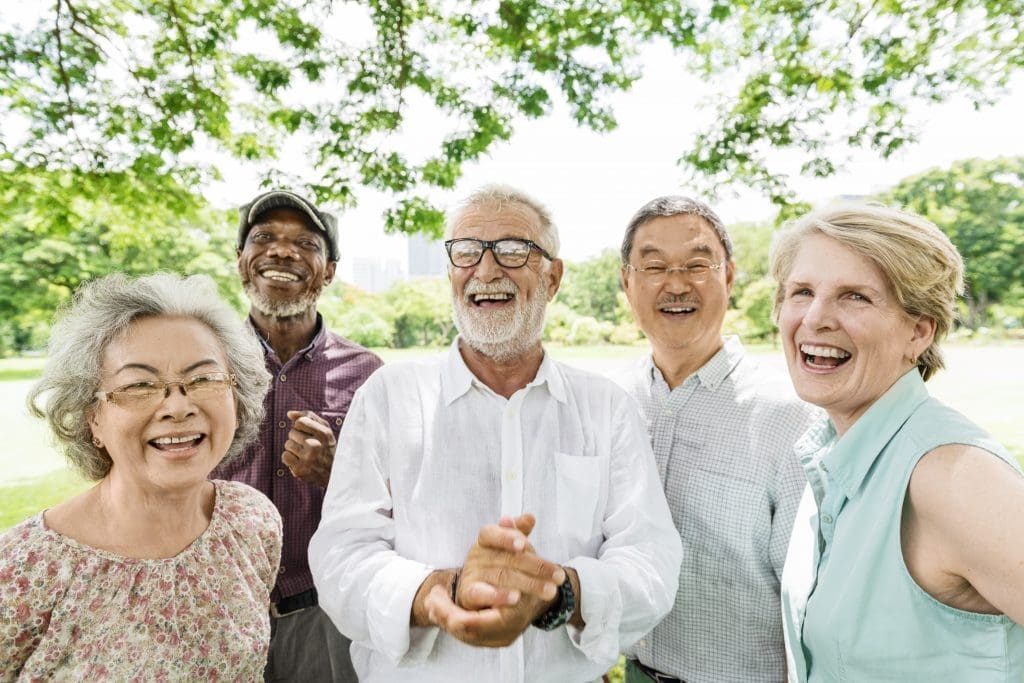 group of seniors smiling and laughing together while outside